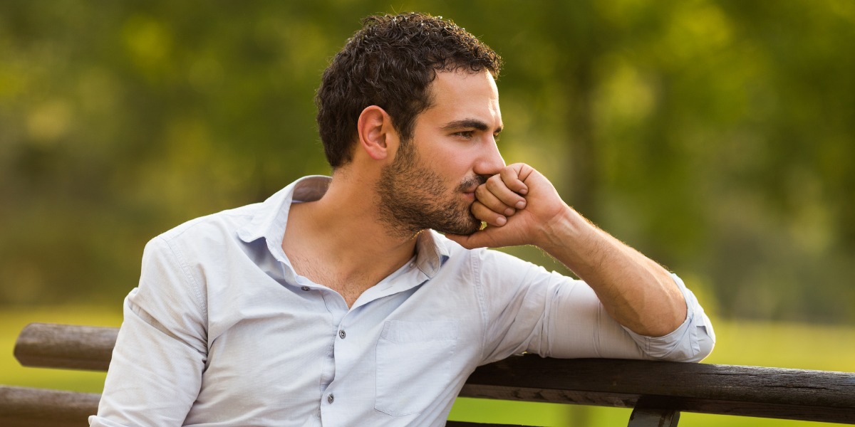 A man sitting alone in distress while considering when to go to rehab for addiction