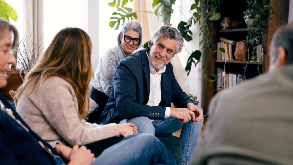 Adults participating in a supportive group setting during long-term rehab for addiction recovery.