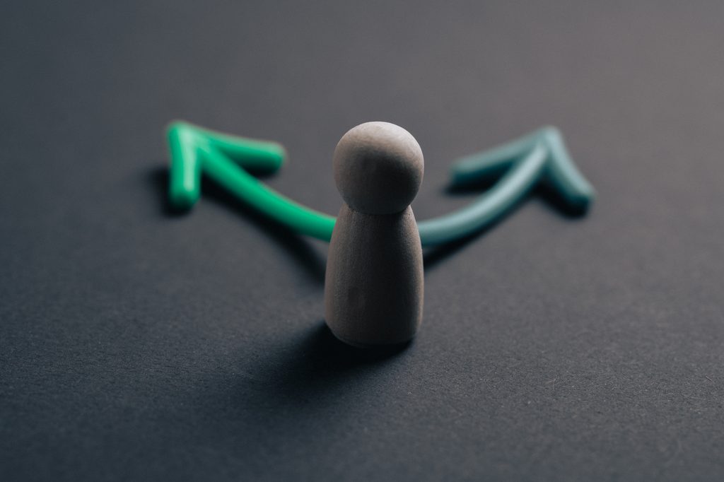 A person facing two different paths representing the choice between inpatient vs outpatient rehab for addiction treatment.